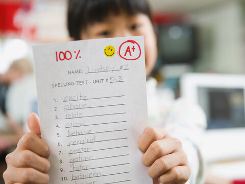 Elementary student holding an A grade paper