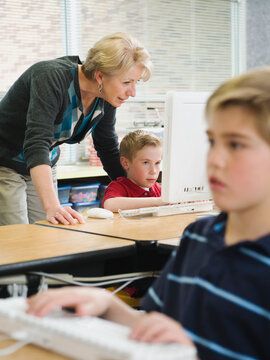 Teacher helping young student in computer lab