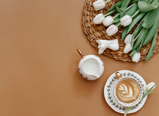 Easter, spring, 8 march, mother day, still life scene. White tulips and coffee cup on brown background, top view, flat lay, copy space