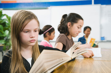 Elementary school students reading books at desk