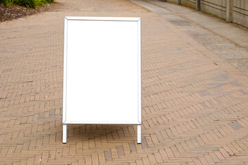 Blank white outdoor advertising stand or sandwich board mockup template. Clear street signage board placed on the pedestrian walkway.  Background texture of standee at a public sidewalk.