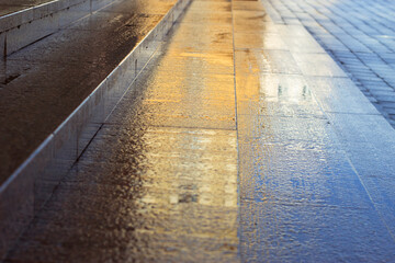Wet granite stairs after rain on the street. City pattern with natural stone stairs and pavement. Colorful sunny background. 