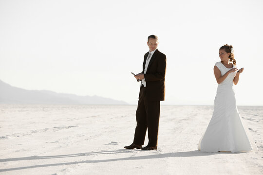 Bride and groom texting in desert