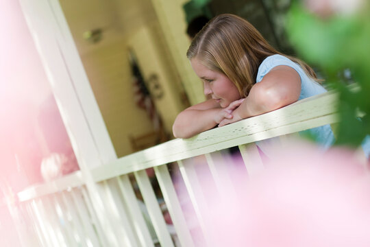 Young girl gazing over porch railing