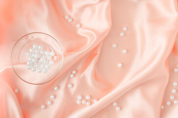 Elegant composition with crystal glass and white pearls on soft silk or satin fabric. Minimal composition. Soft background.
