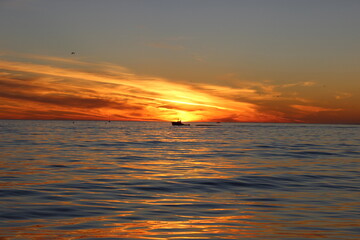 sunset over the sea with boats