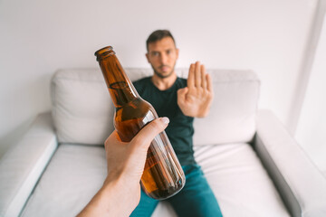 No alcohol. Healthy lifestyle. Young man refuses to drink beer, making stop gesture to bottle of...