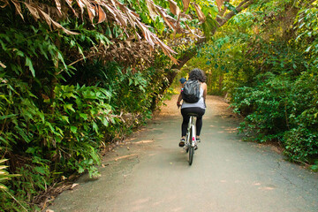 Woman riding a bike on the park full of trees 