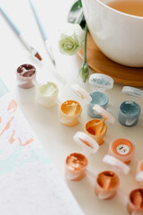 Artistic equipment: paint brushes, paints and painting on work table.