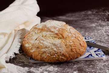 Bread or ciabatta or Italian bread, on table with wheat and a knife beside.