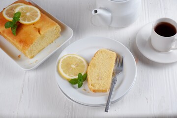 Lemon pound cake with white teapot and a cup of coffee with blury background,white background