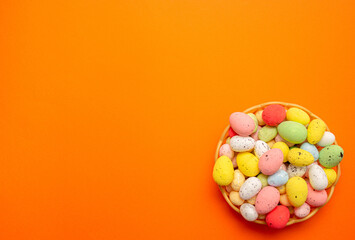 Obraz na płótnie Canvas Colorful Easter eggs in the basket on orange background. Spring holidays concept
