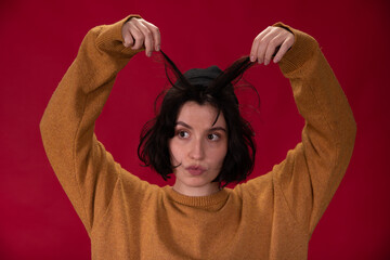 brunette hipster girl in black knitted cap and mustard sweater holding strands with hands like...