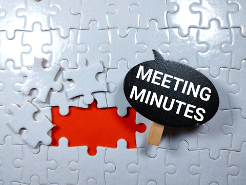 Wooden board with text MEETING MINUTES on puzzle background.Business concept.