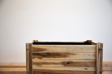wooden empty rectangular pot for plants on white wall background. Wooden planter, raised bed