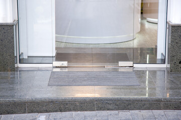 granite gray porch step with a foot mat at the entrance to the central door made of tempered glass...