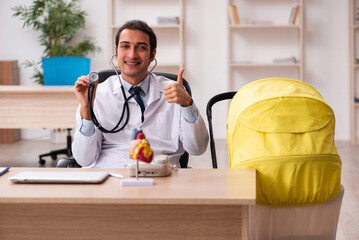 Young male doctor looking after new born in the clinic