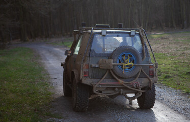 Closeup of a four-wheel drive covered in mud, on a path to the forest © Adam Nowak/Wirestock