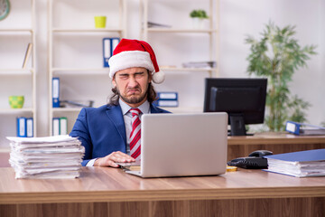 Young male employee working in the office at Christmas Eve