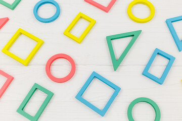 Multicolored wooden toys, blocks on white background. Trendy puzzle toys. Geometric shapes: square, circle, triangle, rectangle. Educational toys for kindergarten, preschool or daycare. Close up