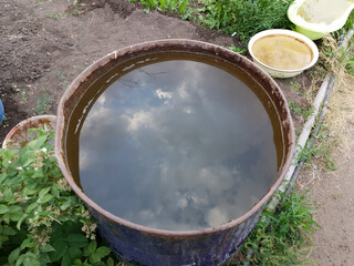 a container with water with a reflection of the sky stands on the ground