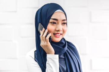 Portrait of smiling happy beautiful muslim woman relaxing using digital smartphone.Young muslim girl talking with friend on phone outdoor