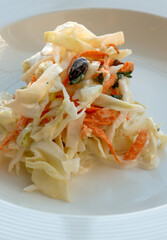 Cabbage salad with raisins on a white plate, cabbage, carrot and mayonnaise.