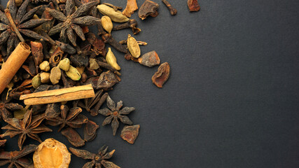 Various spices and herbs such as Star Anise, Cinnamon, Clove and Cardamom in black background.
