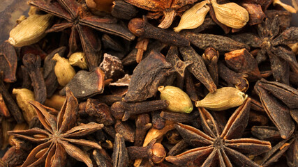 Close up various spices and herbs such as Star Anise, Cinnamon, Clove and Cardamom.
