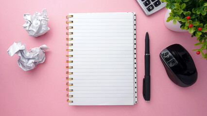 Blank open notebook, pen, crumpled paper wads, calculator, mouse and artificial flower on pink background. Copy space. Top view of blank open notebook, concept of education or business
