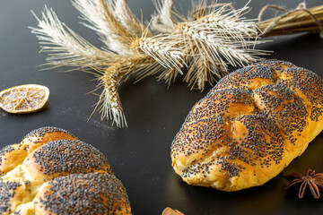 Rye bread isolated. Bakery with crusty loaves and crumbs. Fresh loaf of rustic traditional bread with poppy seeds, wheat grain ear on dark background. Bio ingredients, healthy with seeds.
