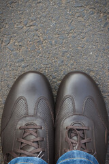 Comfortable brown leather shoes for men on asphalt road or footpath. Male footwear. Copy space for text