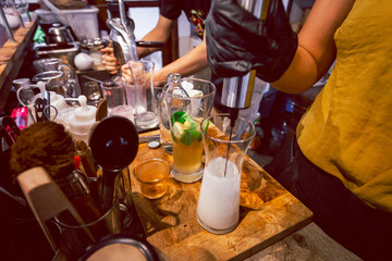 A close-up of a lemon-soda cold drink in a clear glass on the cafe table where the barista is mixing something into the glass. Summer refreshing drink