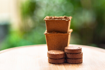Cardboard pots and fibre pellets with blurred background .