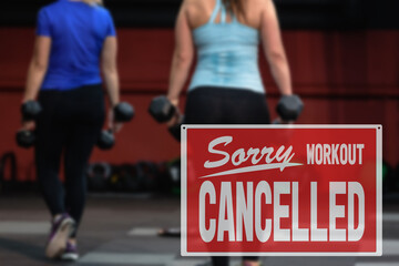 inscription sorry workout canceled. training cancellation due to business closure. Gorgeous brunette lifting some weights and working on her biceps in a gym