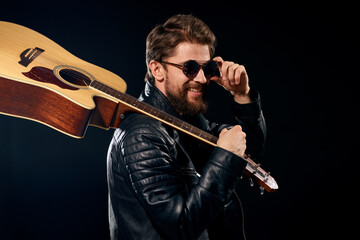 A man with a guitar in his hands leather jacket music performance rock star modern style dark background