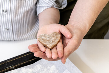 woman's hands holding childs hands with heart shaped pastry. Love and family concept