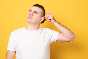 Young handsome man wearing casual t-shirt standing over yellow background confuse and wonder about question. Uncertain with doubt, thinking with hand on head. Pensive concept.