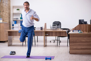 Young male employee doing sport exercises during break