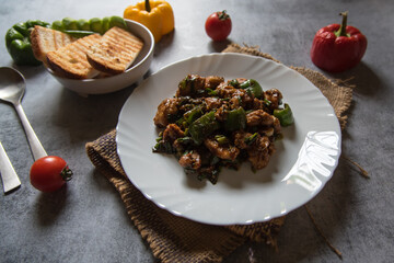 Popular dish chilli chicken and bread slices on a background. Close up, selective focus.