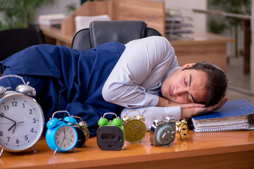 Young male employee sleeping in the office in time management co