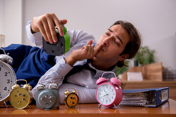 Young male employee sleeping in the office in time management co