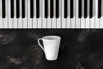 Keyboard of a piano with one white mug in front of it