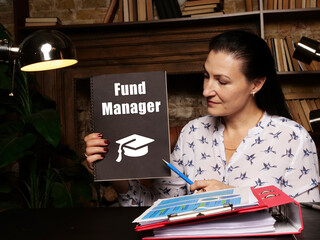 Woman's hand showing black notepad with phrase Fund Manager - closeup shot on grey background