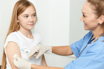 Fototapeta premium female doctor giving an injection to a girl in the hand of a hospital health covid 