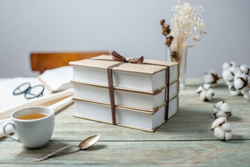 Stack wrapped craft paper books, tied with ribbon on a wooden table. Concept of reading and books...