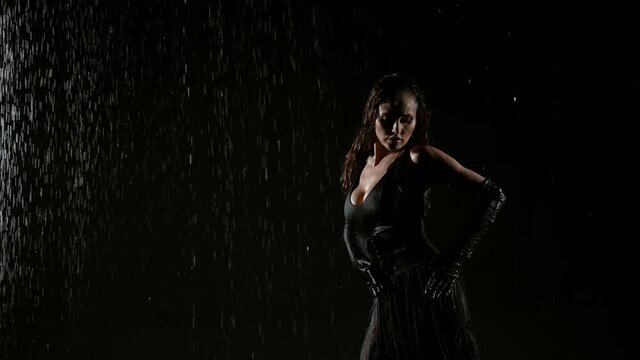 seductive woman is dancing slowly under rain at night, stroking her body and embracing herself