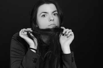 Black and white portrait of young brunette woman in a studio on a black background