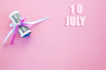 calendar date on pink background with rolled up dollar bills pinned by pink and blue ribbon with copy space. July 10 is the tenth day of the month