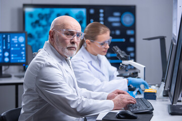 Professor and his young and professional laboratory assistant are doing scientific experiment in a modern laboratory. Genetic engineers workplace. The concept of science, medicine and vaccine.